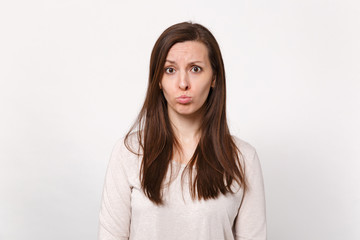 Obraz premium Portrait of disconcerted displeased offended young woman in light clothes blowing lips isolated on white wall background in studio. People sincere emotions, lifestyle concept. Mock up copy space.