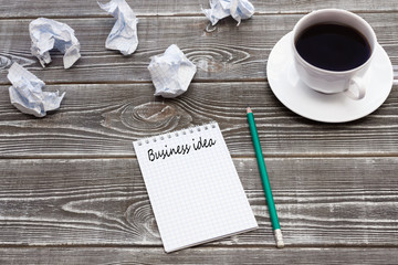 Business ideas written on a notebook, pencil, crumpled paper, a Cup of coffee on a wooden table background.