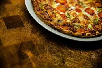 Homemade pizza with cherry tomatoes on dish on dark wooden table.