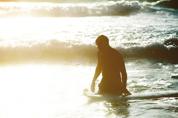 Young man, beginner Surfer learns to surf on a sea foam on the Crete island, beach Falasarna