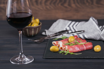 Black stone platter with slices of cured ham or Spanish jamon serrano or Italian prosciutto crudo