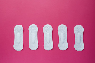 Feminine hygiene pad on a pink background. Concept of feminine hygiene during menstruation. Flat lay, top view.