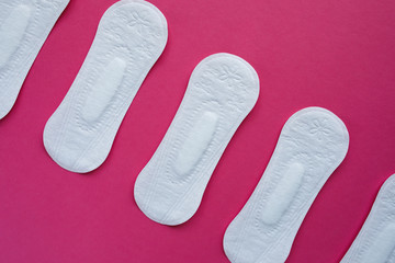 Feminine hygiene pad on a pink background. Concept of feminine hygiene during menstruation. Flat lay, top view.