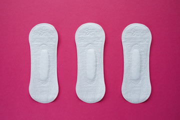 Feminine hygiene pad on a pink background. Concept of feminine hygiene during menstruation. Flat lay, top view.