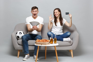 Fun couple woman man football fans support favorite team holding credit bank card, fan of money in...