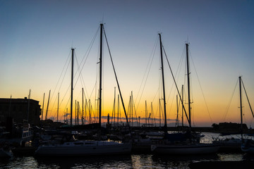Naklejka na ściany i meble The evening sun and yacht mast silhouette