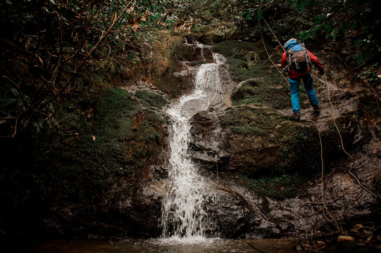Young man dulfers down the mountain with waterfall in Adjara