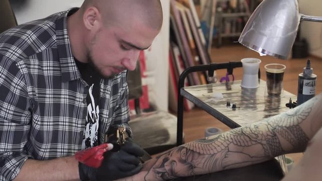 Portrait of a tattoo artist while working, slow motion.