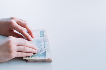 Payment in cash. Money transfer. Currency exchange. Business transaction. Woman passing bundle of Ukrainian banknotes. Copy space.