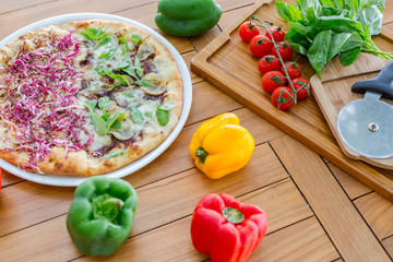 Pizza with tomatoes, mozzarella cheese, black olives and basil. Delicious italian pizza on wooden pizza board. Table top view