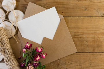 Craft brown envelope with dry flowers on wood background.