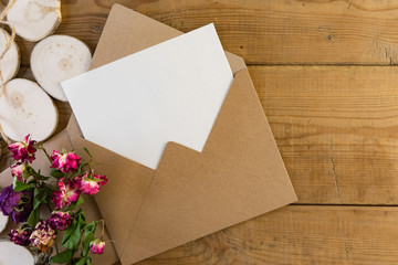 Craft brown envelope with dry flowers on wood background.