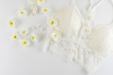 White bra with flowers and pearls on white background.