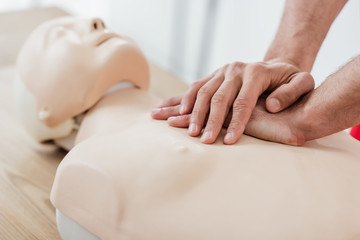 cropped view of man using chest compression technique on dummy during cpr training