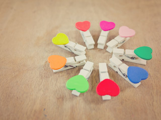 Fototapeta premium Circle consisted of nine wooden clothes-pegs with heart shape. Toned image. Selective focus.