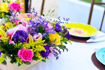table decoration close-up with colorful flowers, flower arrangement, purple, pink and yellow roses, table arrangement
