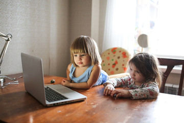 two sisters watch educational videos on laptop