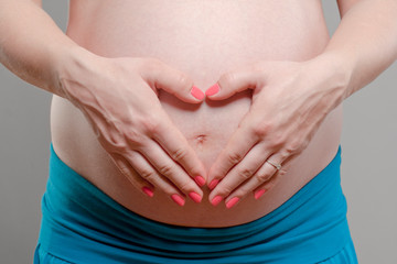 Young Pregnant Woman with Hands Forming Heart Shape.
