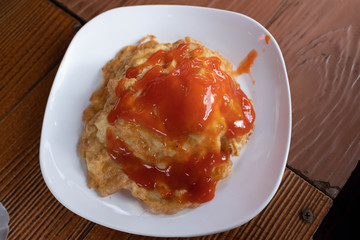 Omelet with chili sauce on a white plate on a wooden table. Top view.