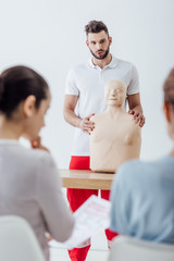 Obraz premium selective focus of instructor with cpr dummy during first aid training class