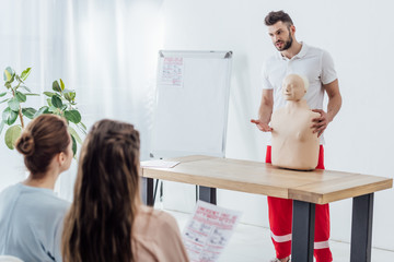 handsome instructor with cpr dummy during first aid training class with women