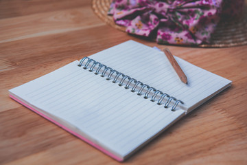 photo of desk, an open notebook with a pencil and hat Placed on the side of the wooden floor