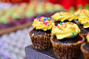 chocolate cupcake with yellow frosting and colored sprinkles