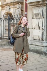 Portrait of a pretty young business lady is negotiating on the phone. The girl uses gadgets. Lifestyle photos. Stylish clothes