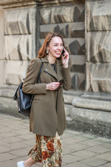 Portrait of a pretty young business lady is negotiating on the phone. The girl uses gadgets. Lifestyle photos. Stylish clothes