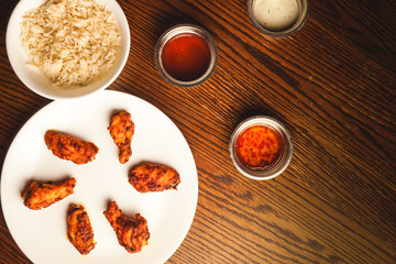 Chicken wings, beer, and dipping sauce on wooden table.