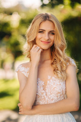 Naklejka premium Young bride stand in the park fron of green background