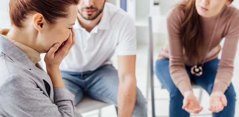 Obraz premium panoramic shot of upset woman crying during group therapy session