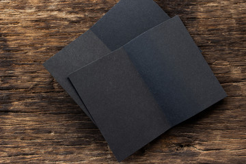 Blank portrait mock-up paper. brochure magazine isolated on brown wooden table, changeable background / Black paper isolated on wood