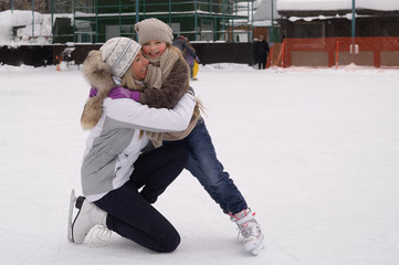 Happy mother and daughter skating on a outdoor skating rink