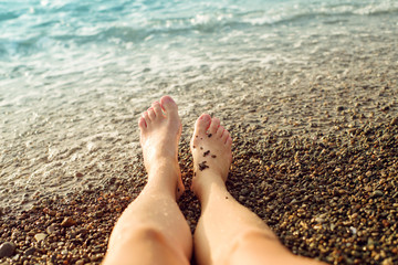Female feet on the pebble beach against the sea, toned. Vacation at the sea