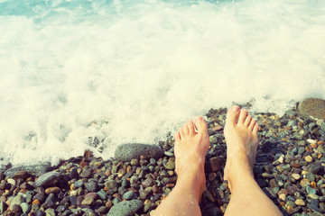 Female feet on the pebble beach against the sea, toned. Vacation at the sea