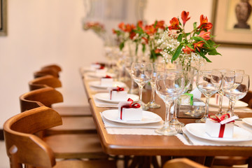 wooden table and chairs setting decorated with red lilies white dishes, glasses of wine and water, table setting, table set, chrystmas table, table setting