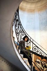 Young beautiful woman sitting on old round spiral staircase.