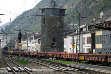 Fototapeta premium Güterzug auf der Rheinstrecke bei Kaub nahe an Häuserreihe mit Bahnlärm im Mittelrheintal - Stockfoto