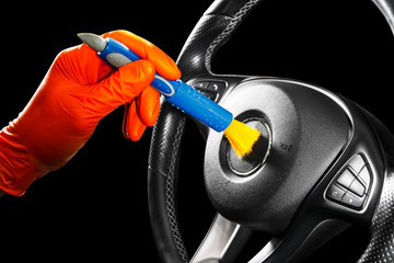 A man cleaning car steering wheel with brush. Car detailing or valeting concept. Selective focus. Car detailing. Cleaning with sponge. Worker cleaning. Car wash concept solution to clean