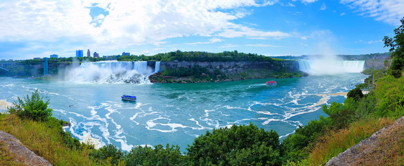 Panoramic view of the both Canadian and American sides of Niagara Falls under blue skies