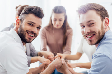 group of people sitting, smiling and stacking hands during therapy session