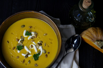 pumpkin soup on a wooden background with olive oil, pumpkin, pumpkin seeds and cream cheese