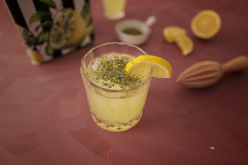 Homemade lemonade with mint and ice, served with fresh lemons on orange table. Food and drink frame