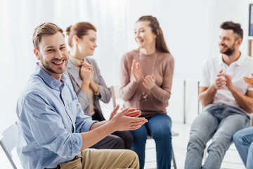 group of people smiling and applauding during support group session