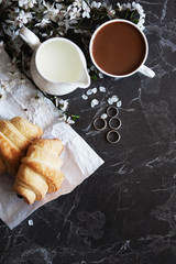 concept of morning breakfast. Fresh croissant and a cup of hot coffee with milk.