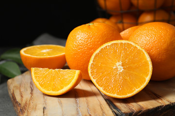 Wooden board with ripe oranges on table, closeup