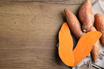 Flat lay composition with sweet potatoes and space for text on wooden background