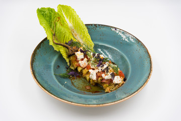 Baked pepper with tomato, cheese and dill on the blue plate.