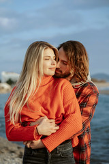 Boyfriend hugging and kissing young girl on beach. Holidays at sea on vacation. Portrait at sunset.